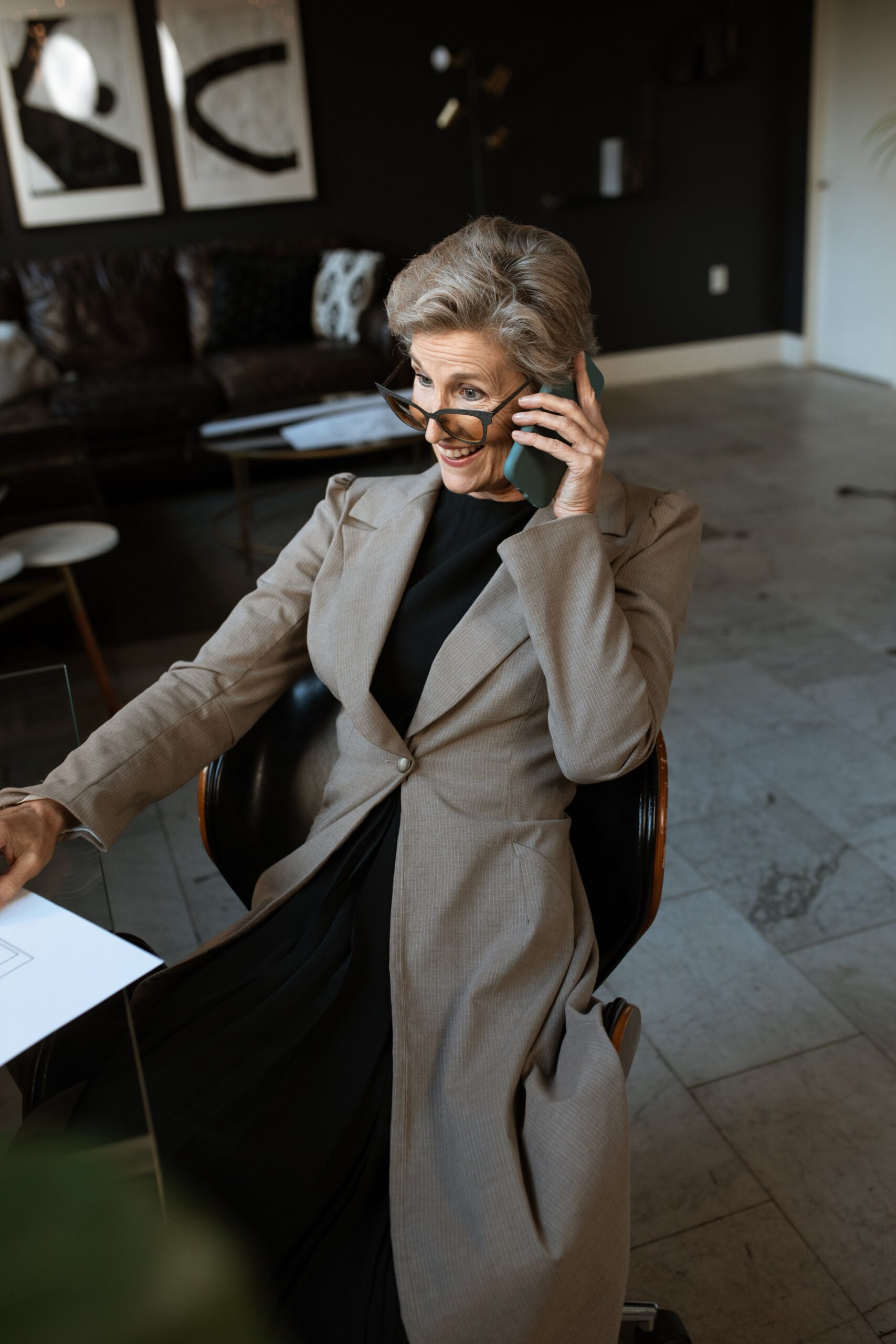 Professional woman on phone smiling at desk with papers. 