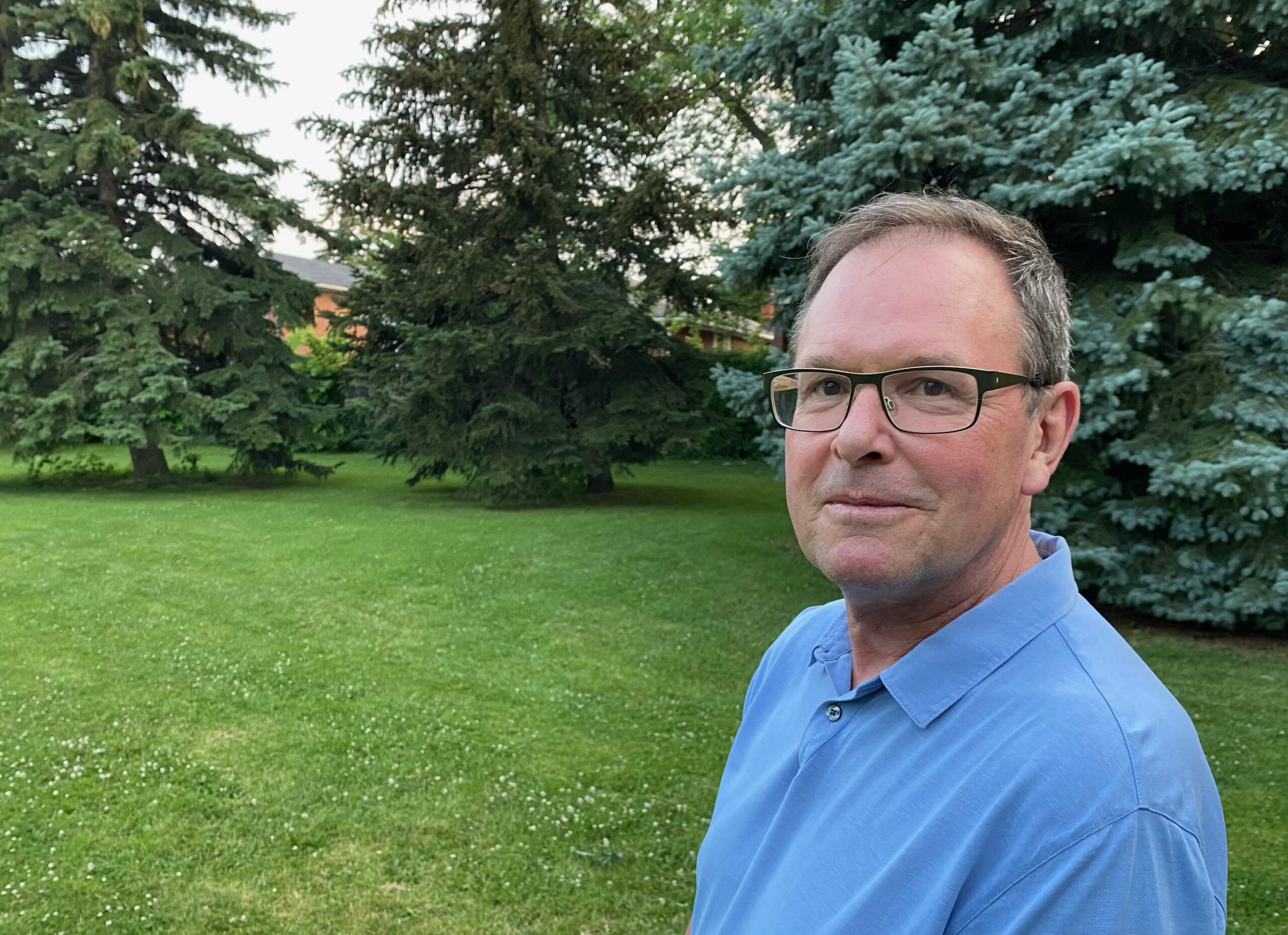 Luke Moore, CM, smiling outside a green lawn. 