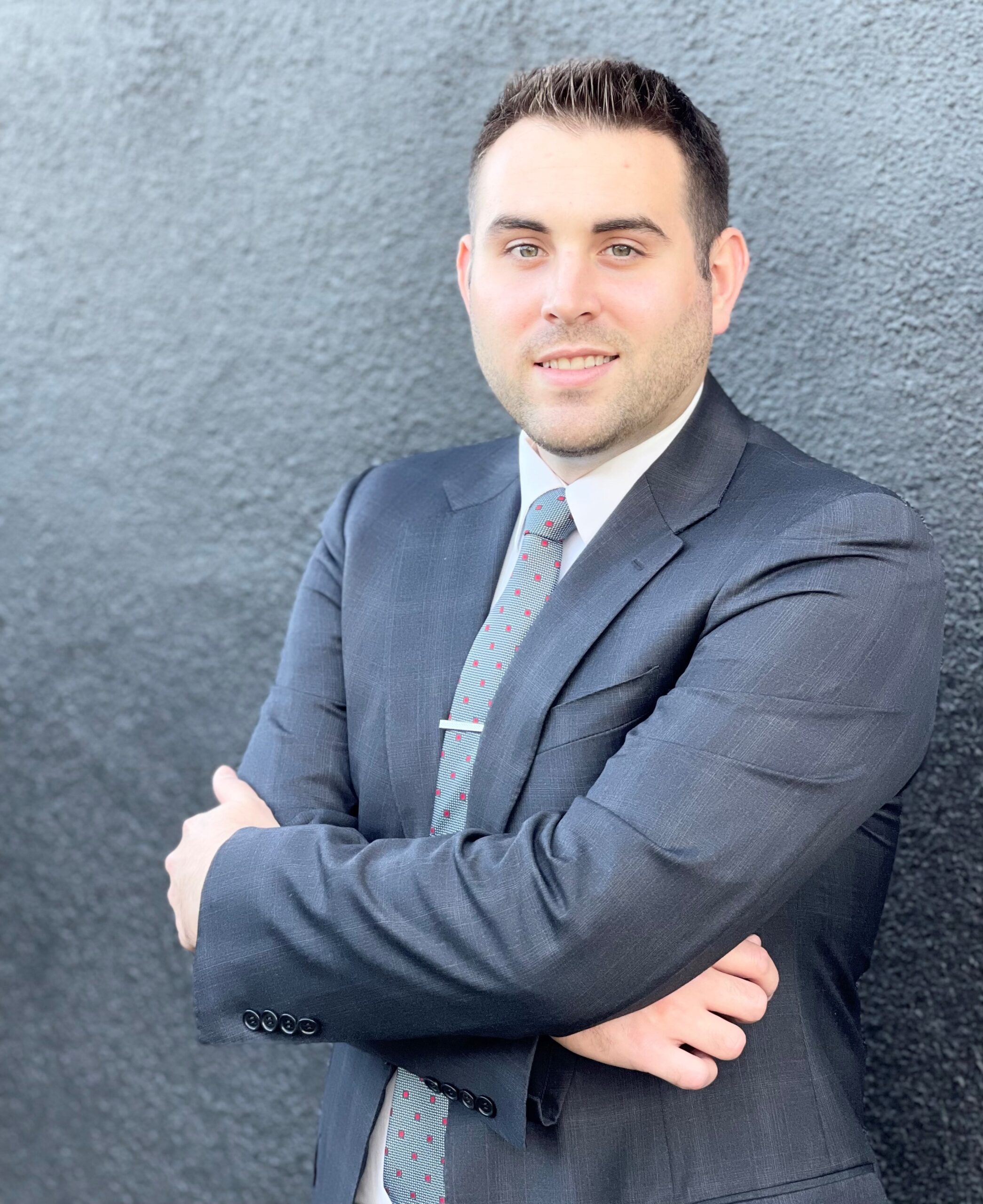 Jordan Swerid, CM, with arms crossed in front of brick wall. 