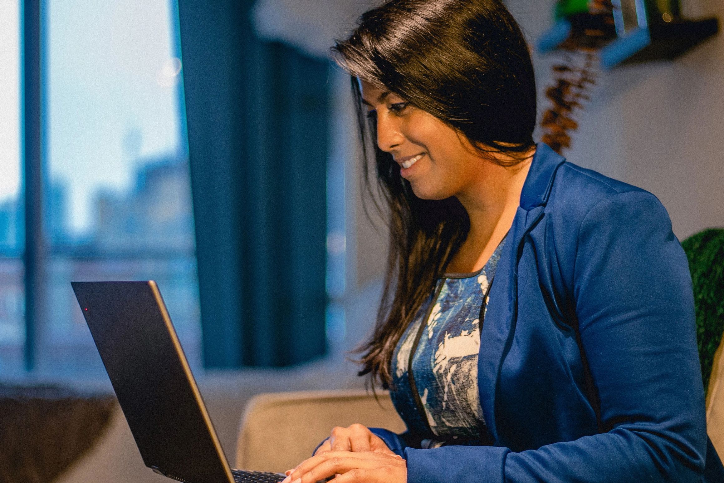 Roshni Wijayasinha, CM, smiling and typing on laptop.